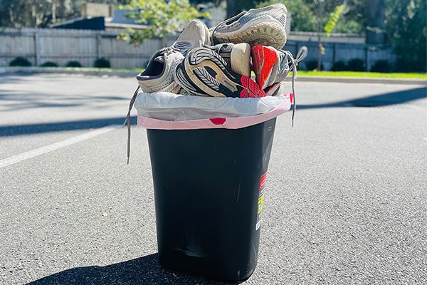 running shoes piled into a trash bin