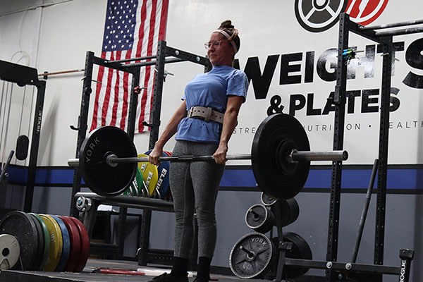 lifter locking out a deadlift at weight and plates gym