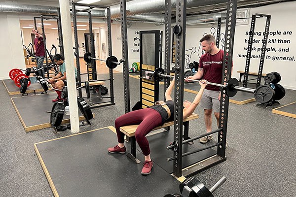 michael helps Holly rack the bar after a set of bench presses
