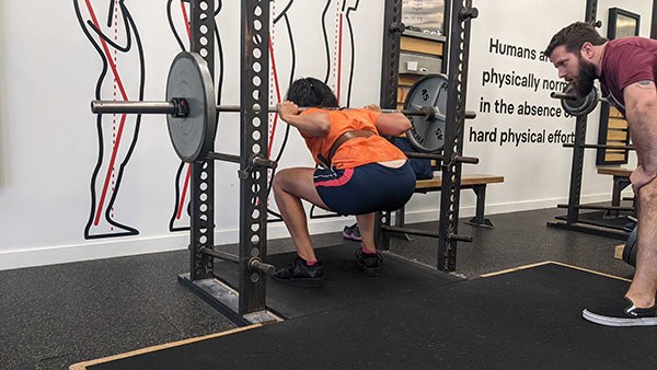 tony stein coaches priya through her first set of squats at 135