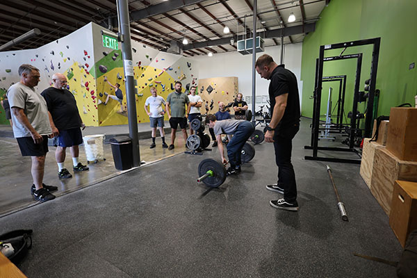 grant in the middle of teaching the deadlift start position at a starting strength training camp