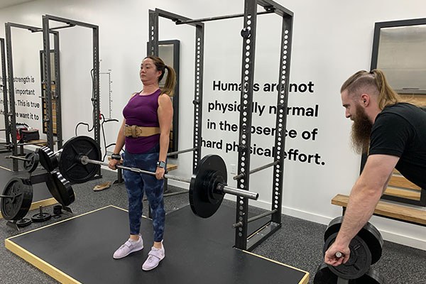 apprentice dan buege coaches a lifter through a set of deadlifts