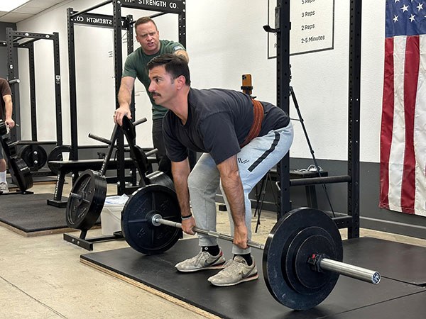 grant broggi coaches lumbar extension on a deadlift during a starting strength training camp