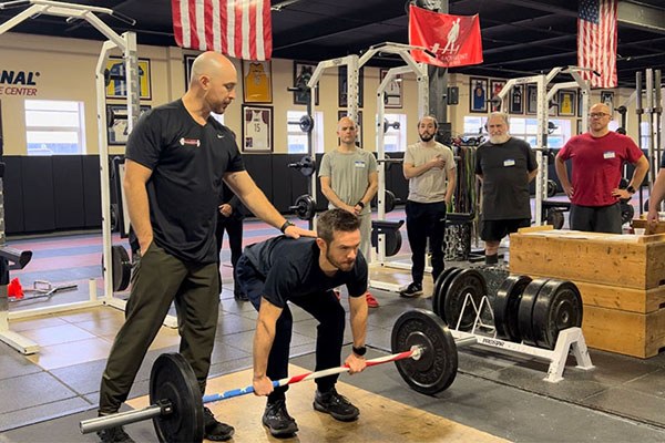 chris palladino teaches a lifter how to set his back at a starting strength training camp