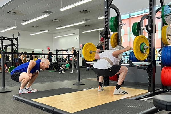 chris palladino uses tactile and verbal cues to get a visually-impaired lifter squatting correctly