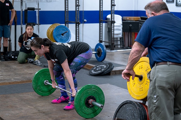 dee platero prepares to start a power clean at the starting strength seminar
