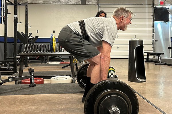 robert santana coaches lawrence at the start of his deadlift