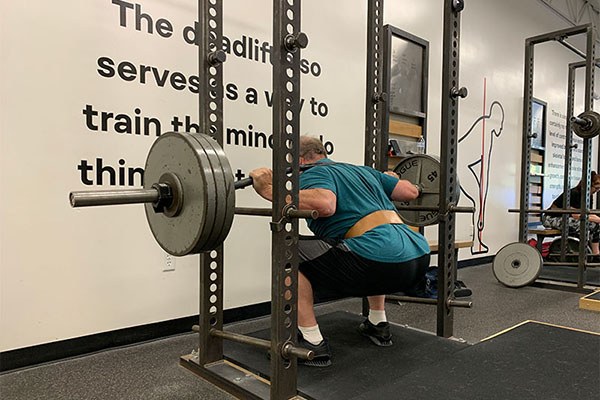 marcus uses a cambered bar at starting strength austin to work around injuries