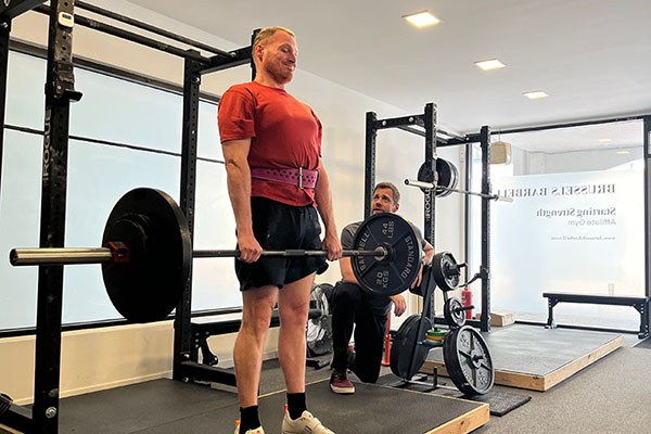 ken locks out a deadlift at the starting strength camp as steve ross coaches him through the lift