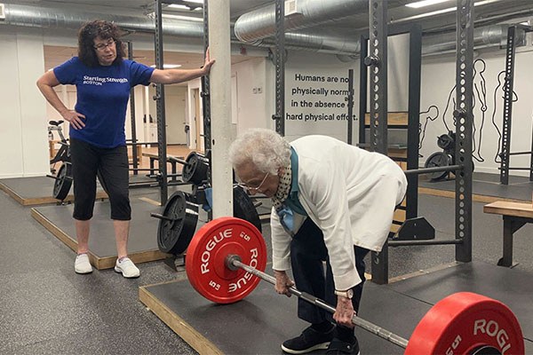 apprentice marie watches a lifter deadlift at starting strength boston
