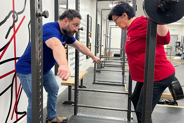 a coach using an exaggerated cue to help a lifter move correctly