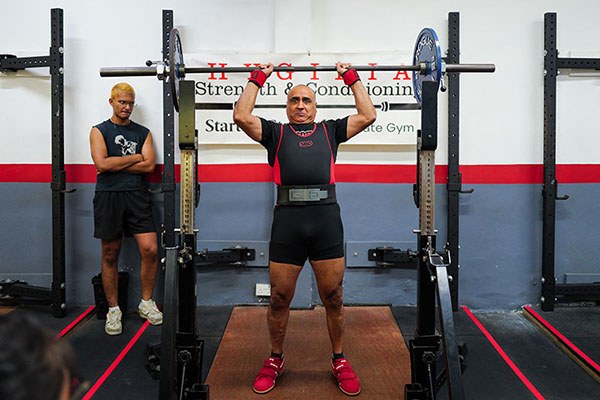 raj grover in the middle of a press at a strengthlifting meet