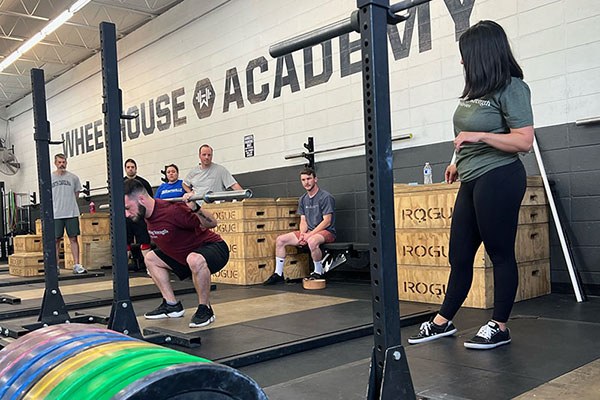 victoria coaches a lifter at a starting strength training camp