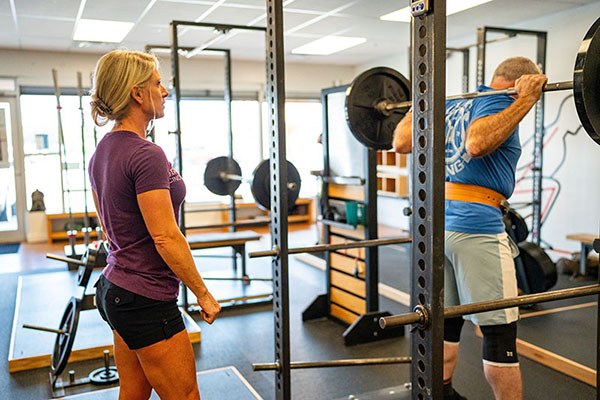 camisha coaches paul as he begins to squat