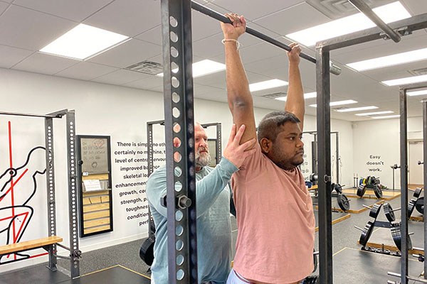 adam uses a tactile cue to help a lifter shrug into his press lockout
