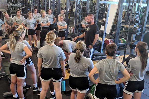 jared nessland with a group of athletes in the weight room