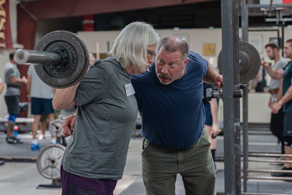 mark rippetoe coaches an older lifter at a starting strength seminar