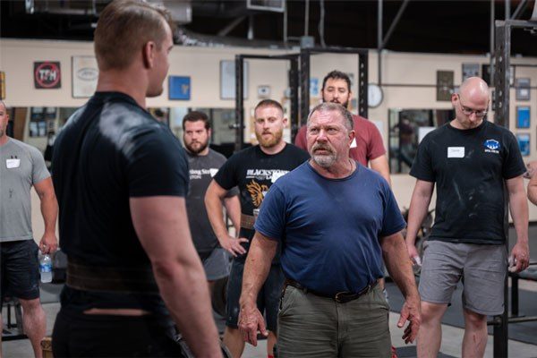 mark rippetoe teaches on the platform at a starting strength seminar