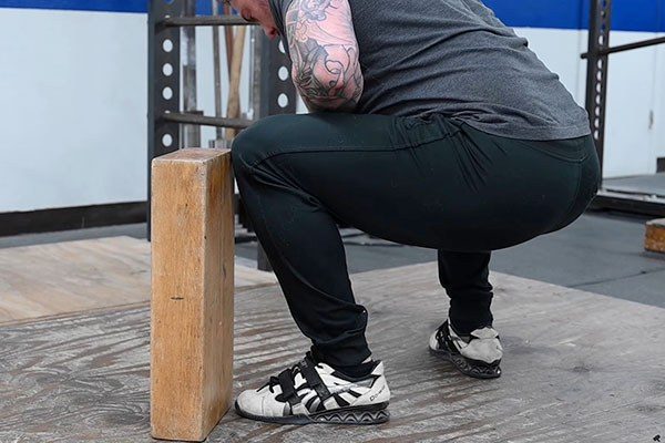 lifter with knee against tubow at the bottom of a squat