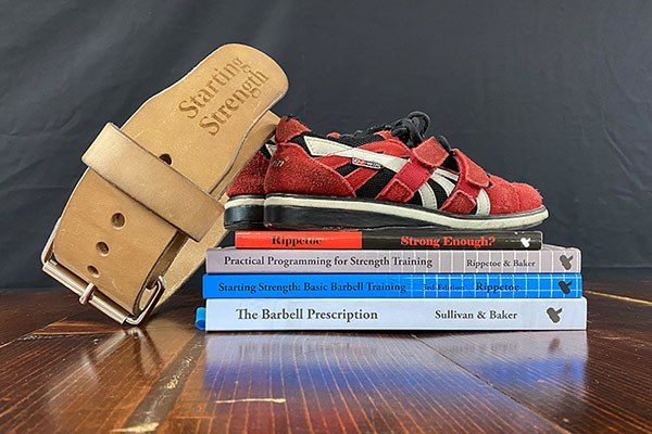 stack of coaching gear books lifting shoes belt