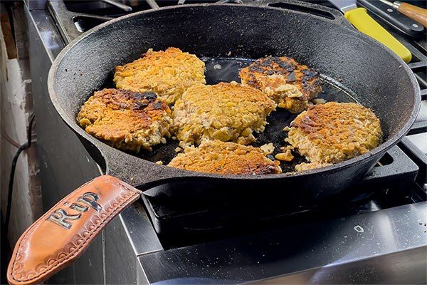 salmon patties cooking in a cast iron pan
