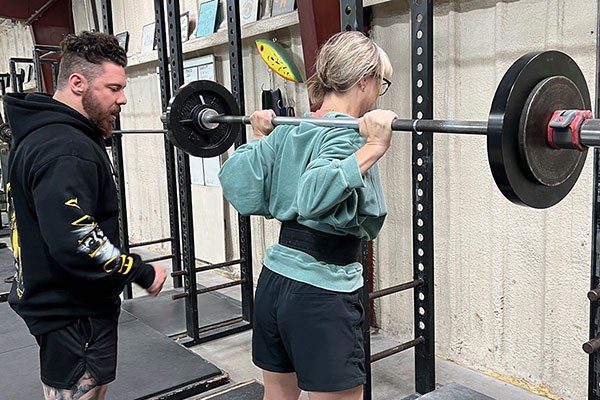 lifter getting coached through a squat