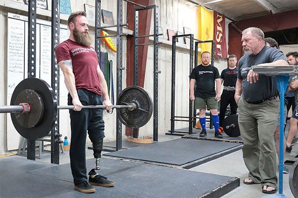 lifter locking out a deadlift at a starting strength seminar