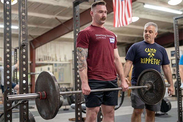 lifter being coached in the deadlift at a starting strength seminar