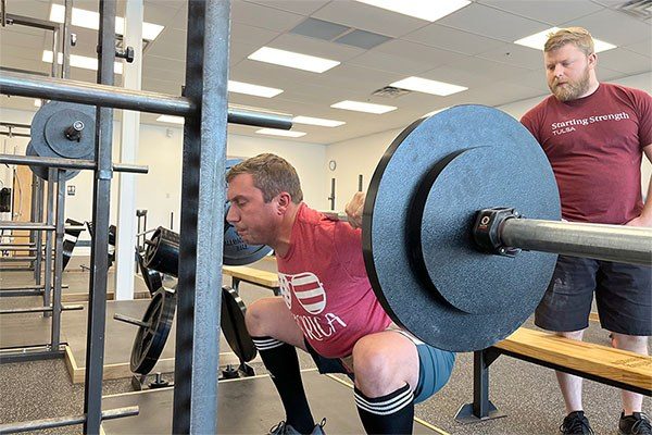 andrew lewis coaching the squat at a starting strength gym