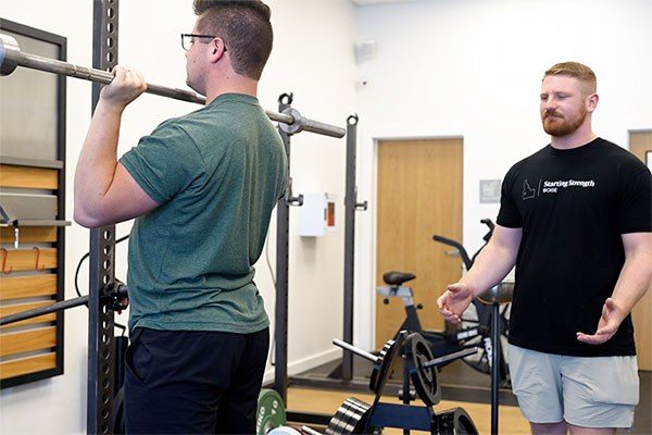 coach observing a lifters hips in the press