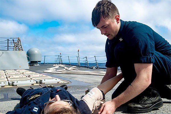 man applying pressure bandages to a casualty