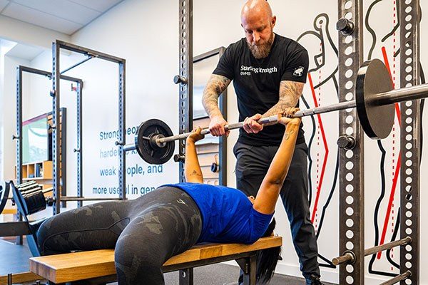 coach handing off a bench press to a lifter