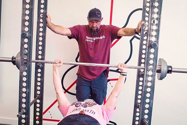 denise working on her bench press as her coach spots