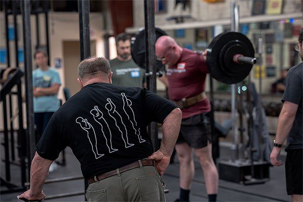 mark rippetoe coaching a lifter squatting at a starting strength seminar