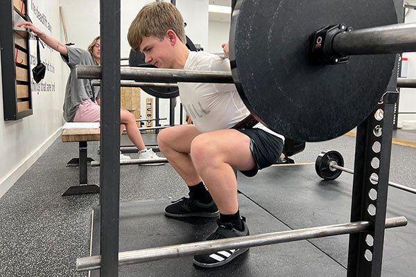 boy at the bottom of a squat inside a rack