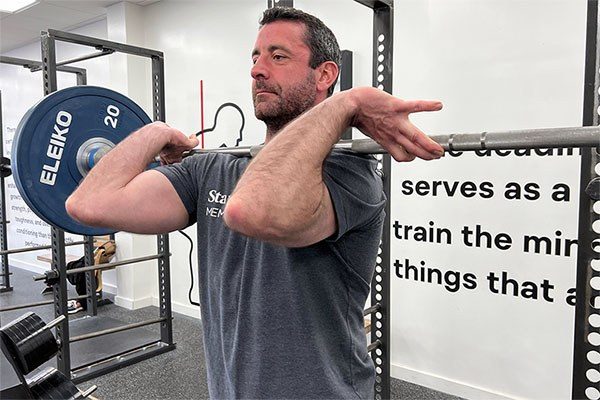 a lifter holds a power clean at the finished rack position