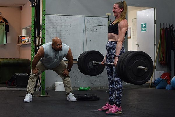 carl raghavan coaches a lifter as she locks out a deadlift
