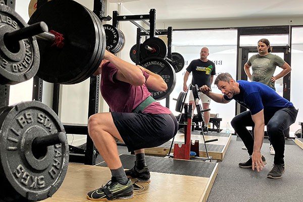 steve ross coaching a lifter at the bottom of a squat