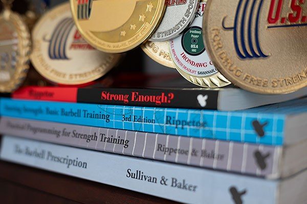 a stack of books draped with lifting medals